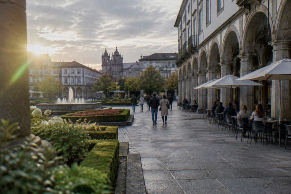 A granite arcade street in Braga's historic centre with café tables and pedestrians in the late afternoon