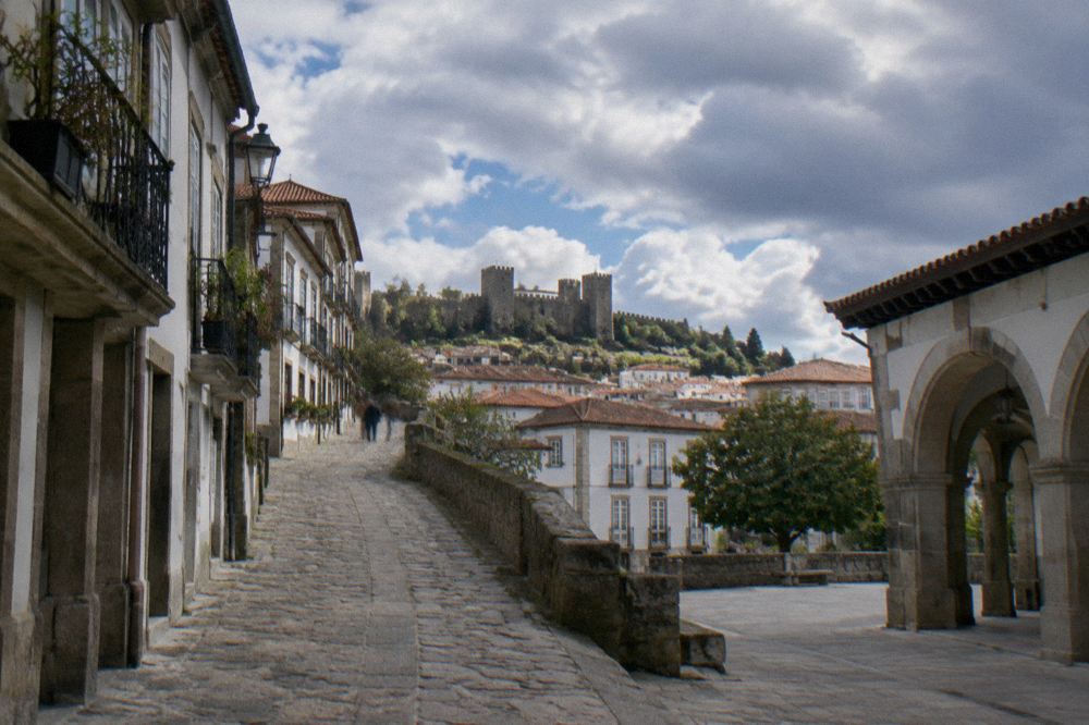 Stone lane rising toward Guimarães castle with the town rooftops below