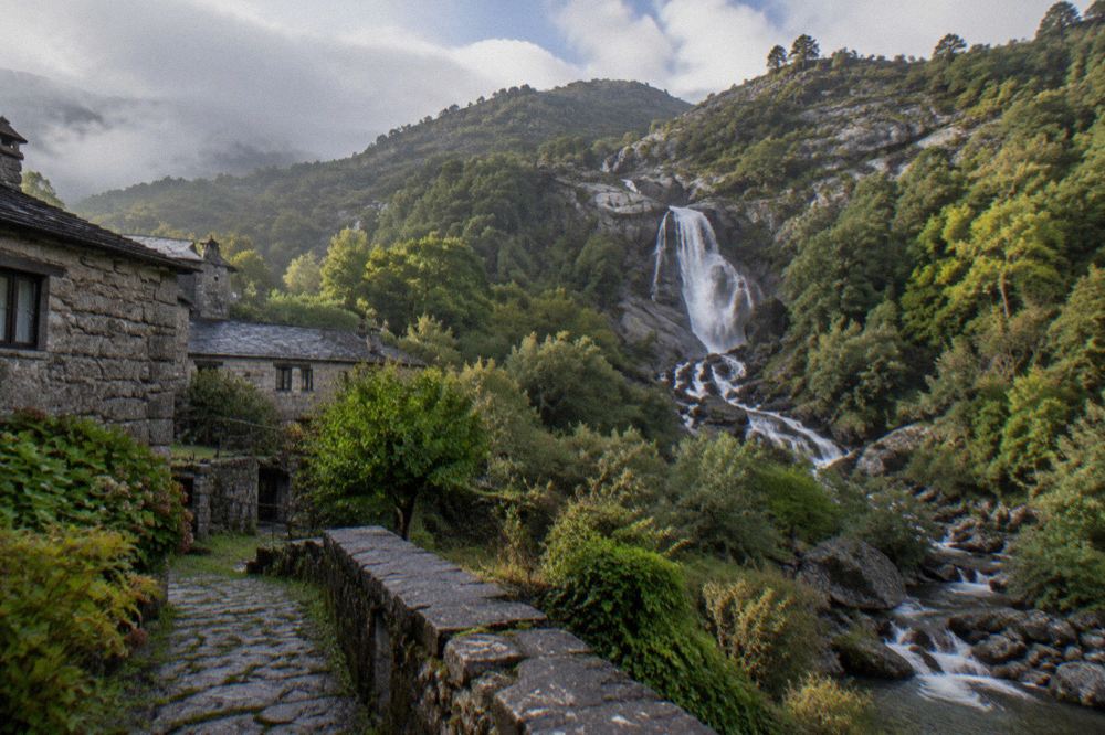 A granite waterfall dropping through green forest in the Gerês valley