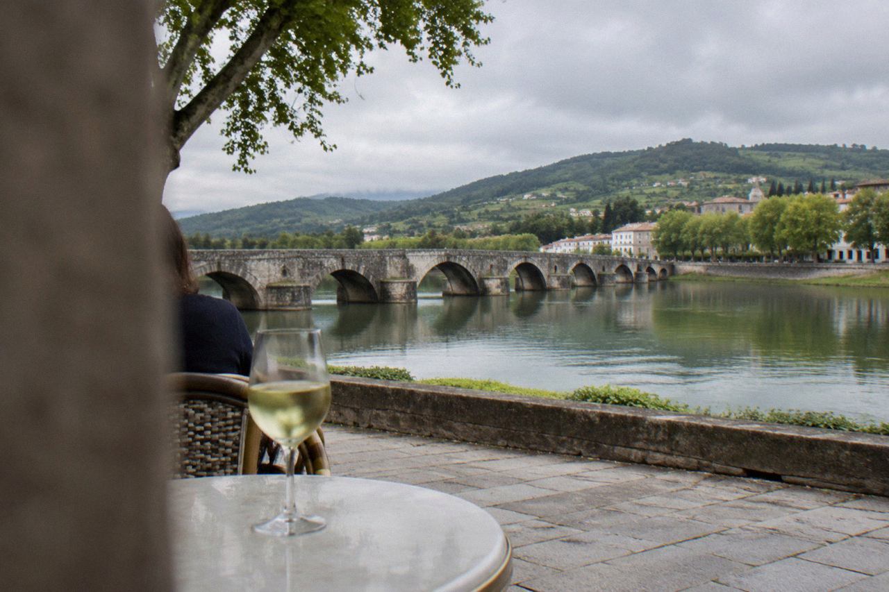 A glass of pale vinho verde on a café table in a historic square