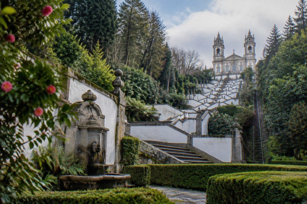 A granite fountain and zigzag stairway section at Bom Jesus do Monte seen through clipped box hedging