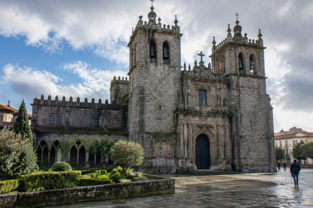 The twin towers and ornate baroque doorway of Braga Cathedral seen from the square in front of it on a bright day