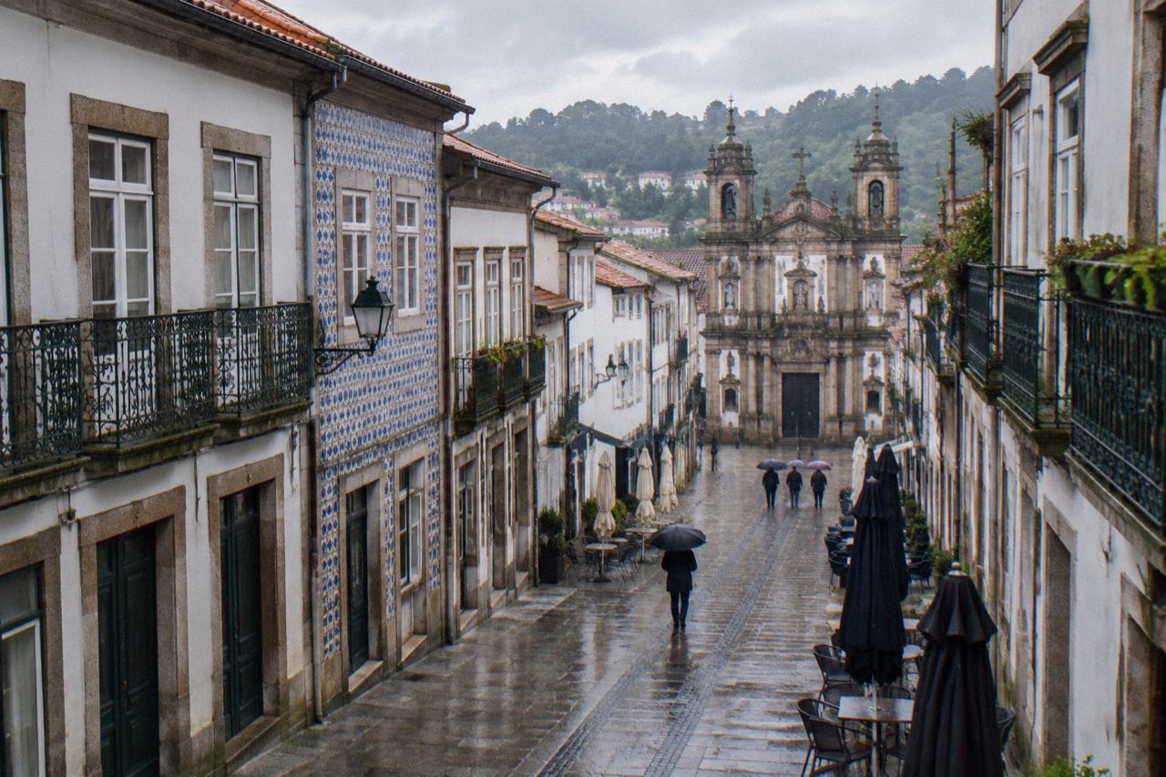 Wet cobblestone street in Braga with rain-slick paving and umbrellas outside closed café doors