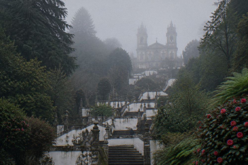 Baroque stairway and sanctuary of Bom Jesus do Monte seen through morning mist above Braga
