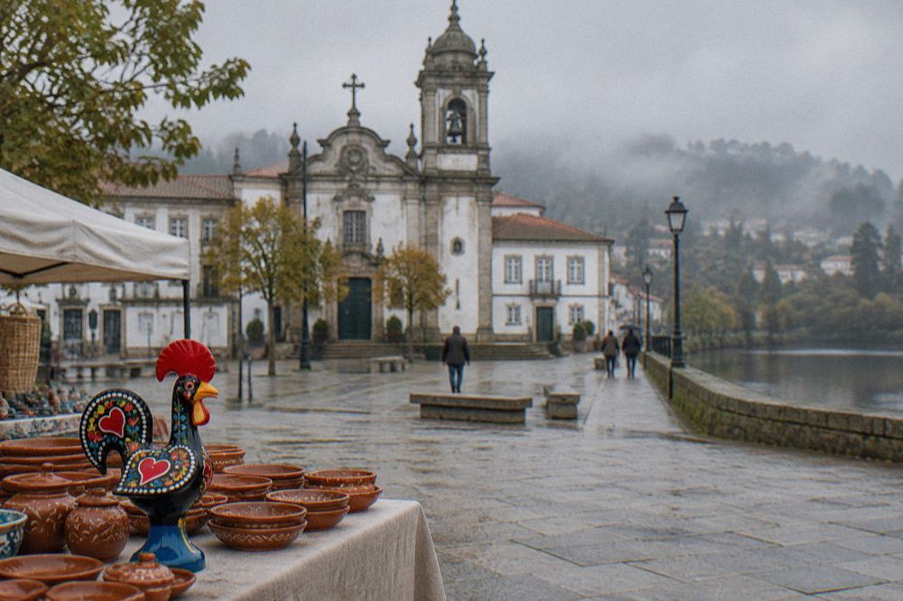 A painted ceramic rooster figure beside clay dishes on a market stall table