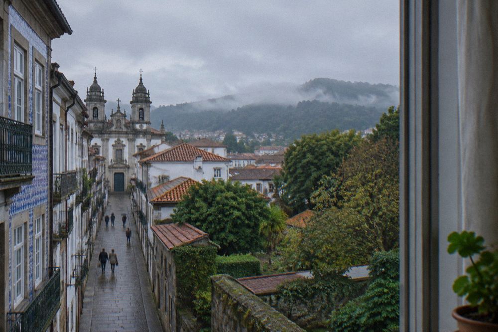 A guest room window in Braga overlooking gardens and rooftops toward the eastern hills