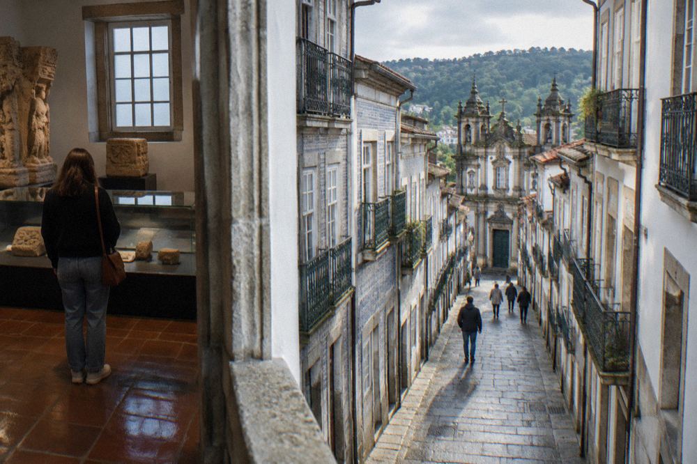 A visitor reading display cases inside a Braga museum with stone carvings and tiled floors