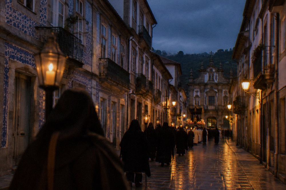 A candlelit religious procession moving through a Braga street at night during Holy Week