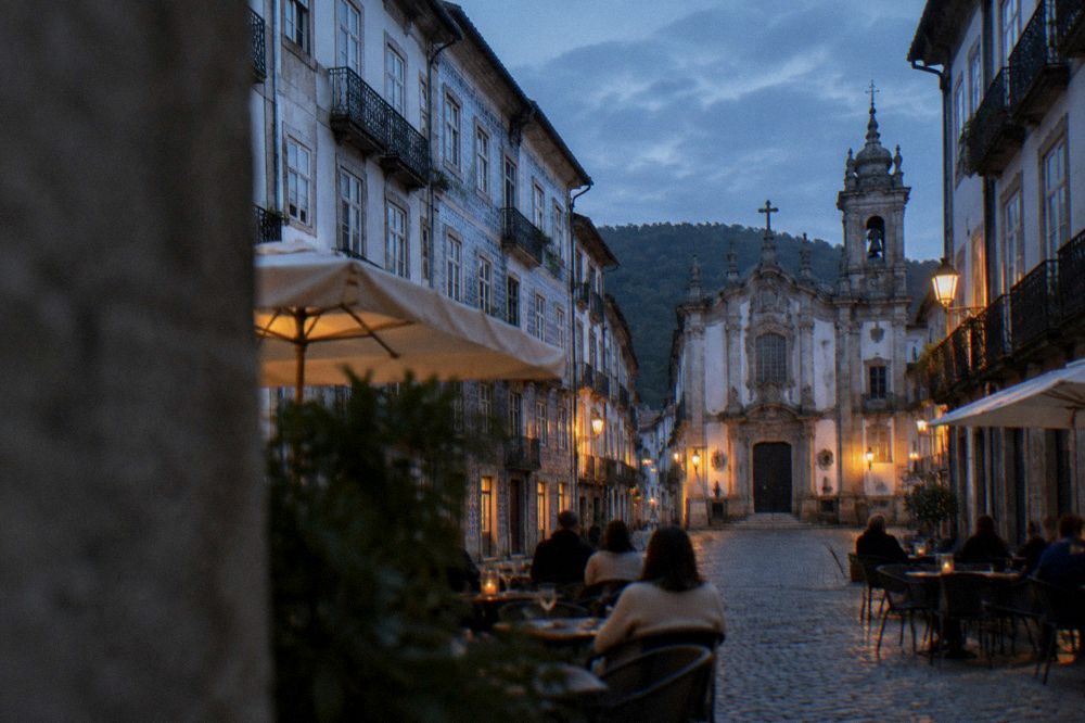 People seated at a cafe terrace on a cobbled square in the evening