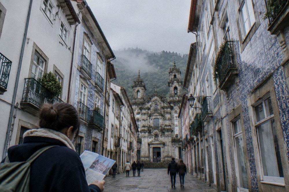 A visitor looking at a museum ticket and a city map at a counter in Braga