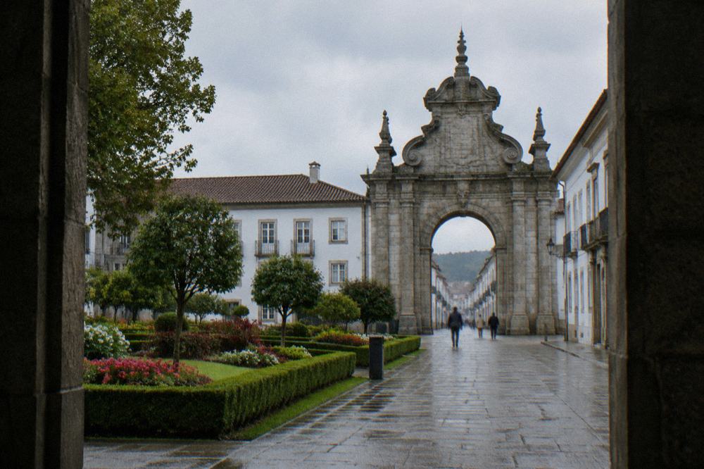A formal city garden with clipped hedges and flower beds near the old city gate in Braga