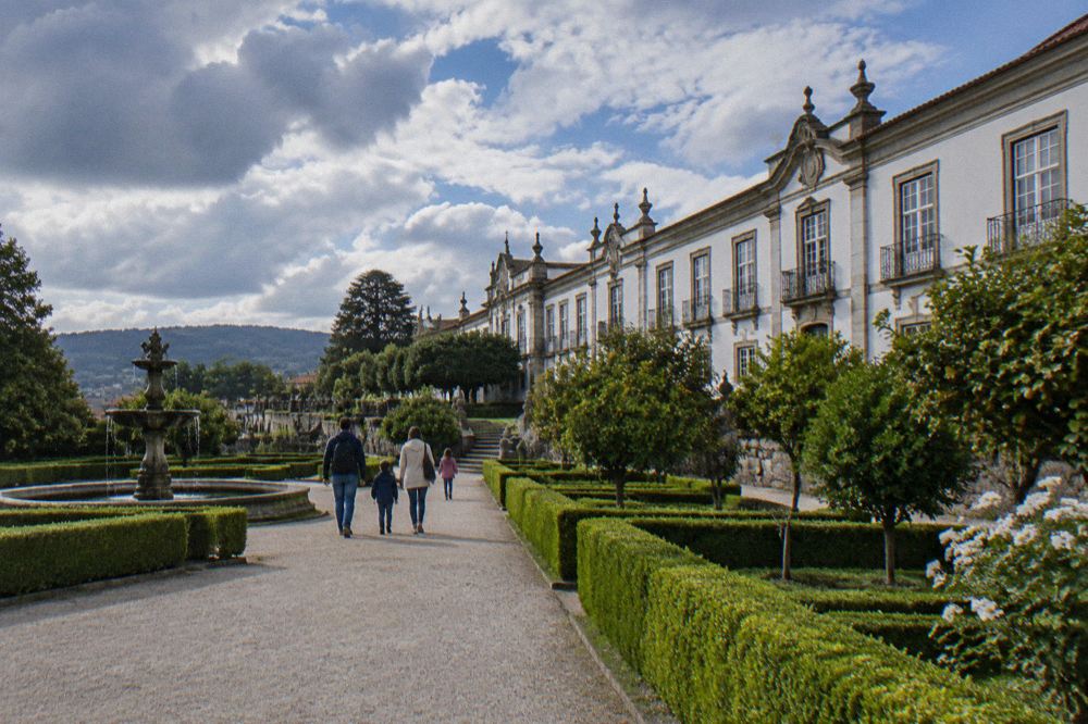 A family walking along a gravel path between clipped hedges in the museum garden
