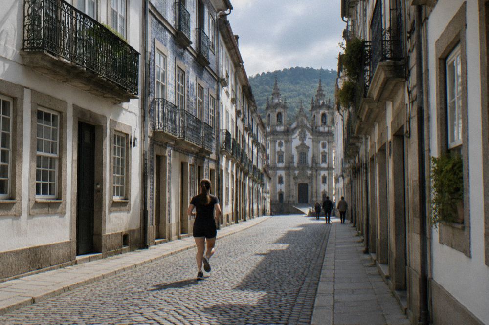 Narrow cobbled street in a Portuguese historic centre leading uphill toward old stone buildings