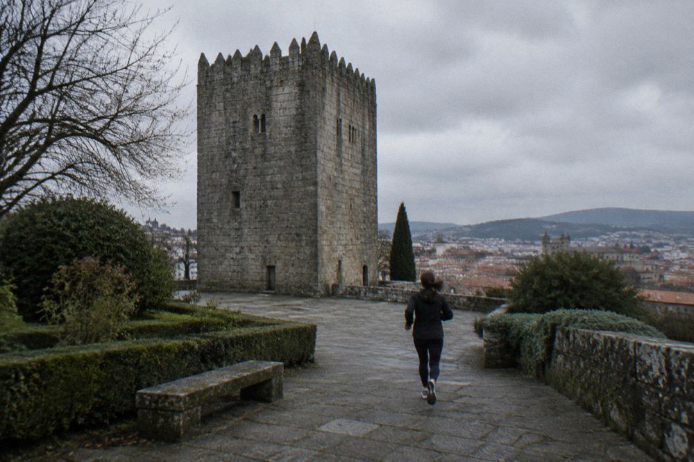 Granite medieval tower seen from a garden terrace with city rooftops beyond