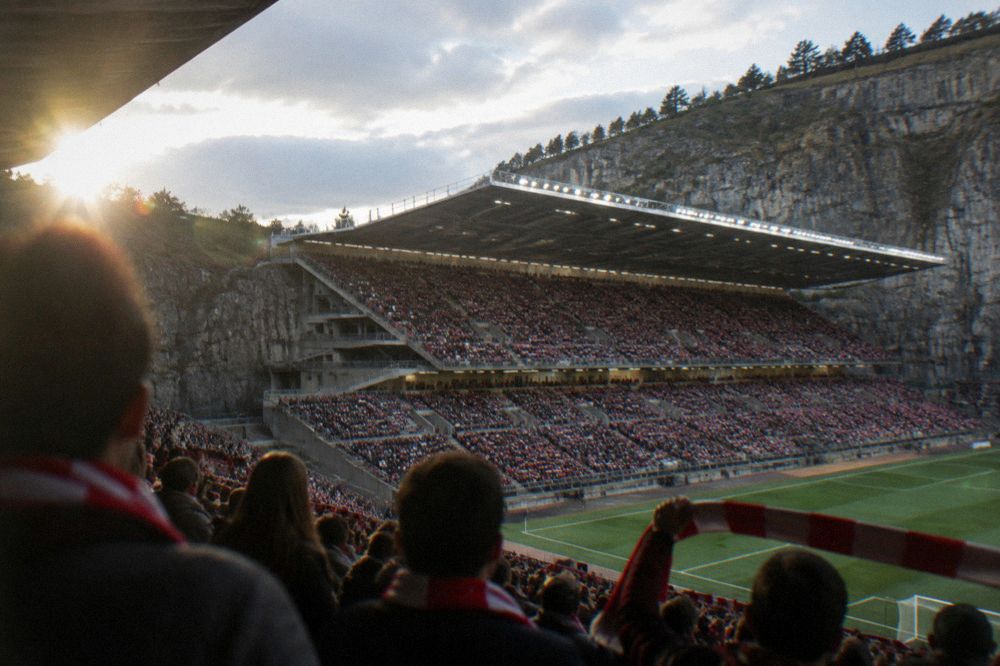 A stadium stand filled with spectators in red and white scarves before a football match