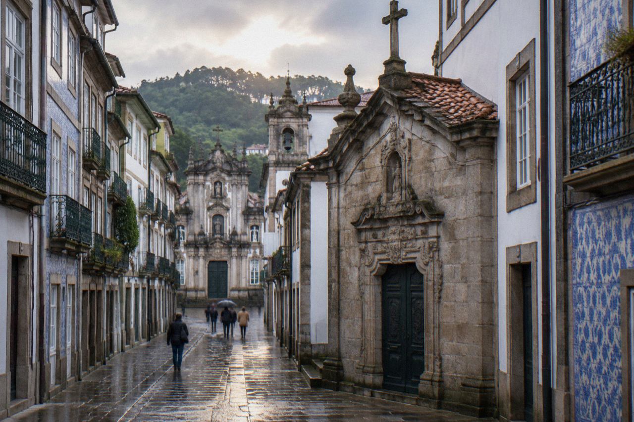 A small stone chapel with an ornate carved portal standing on a narrow street in Braga