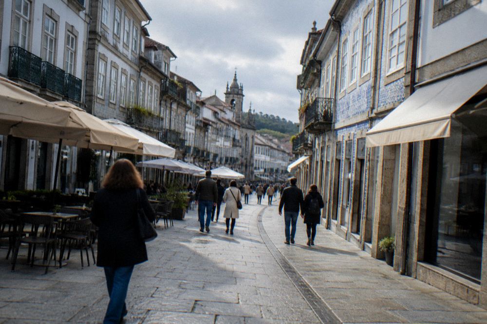 People walking on a pedestrian shopping street in Braga with café awnings and old facades