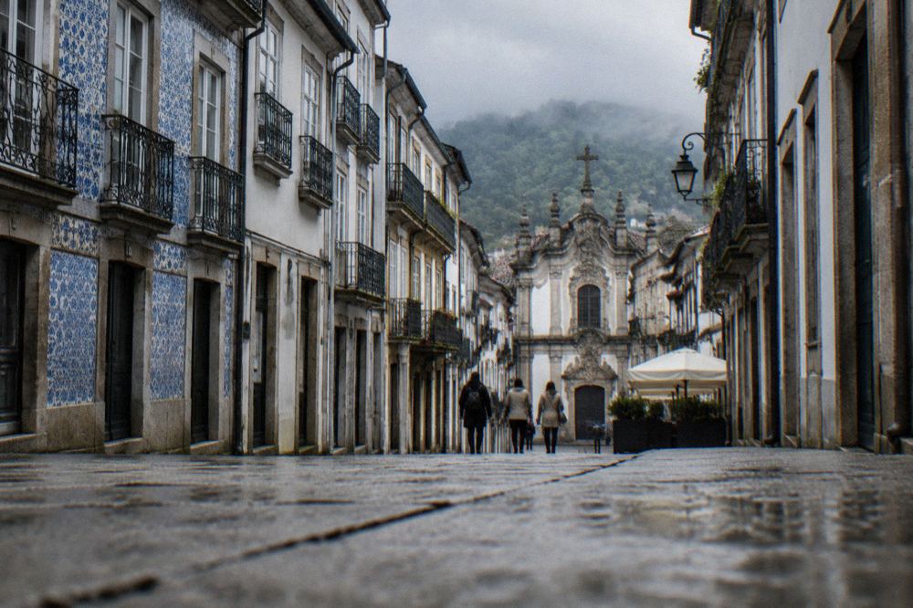 City avenue in Braga leading towards a church façade with pedestrians and old buildings