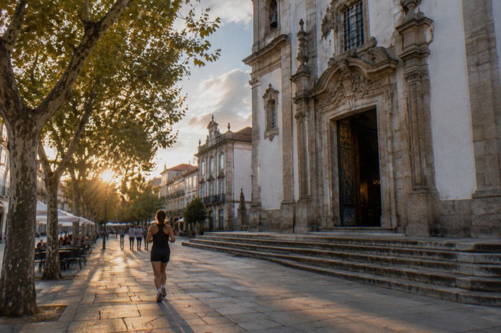 Sunlit pedestrian street in a Portuguese city with historic buildings and café tables
