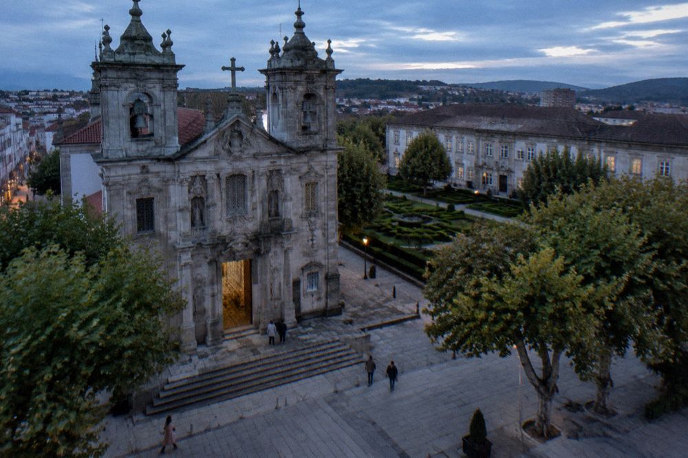 Formal garden with trimmed hedges and a historic building in a Portuguese city