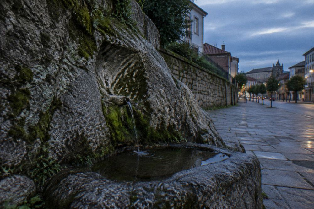 A shallow carved water basin set into the base of a granite rock face