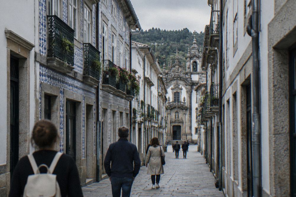 Visitors walking a narrow historic street in Braga towards a museum entrance