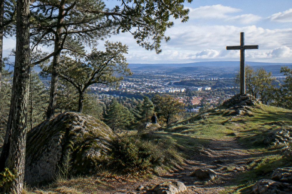 A wooden summit cross standing on a grassy hilltop with a wide horizon