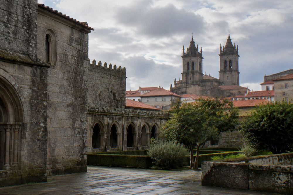 Twin granite towers of a cathedral rising above red-tiled rooftops in a Portuguese city