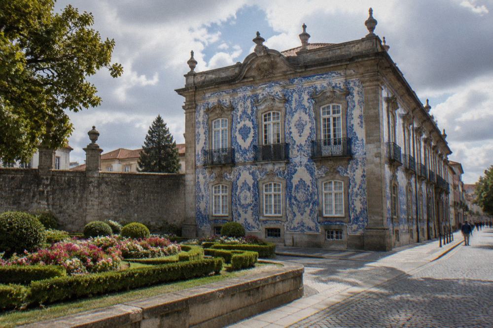 Formal garden with flower beds and a stone palace wall in a Portuguese city