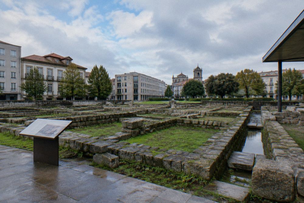 Interpretive panel beside excavated Roman wall foundations in a city square