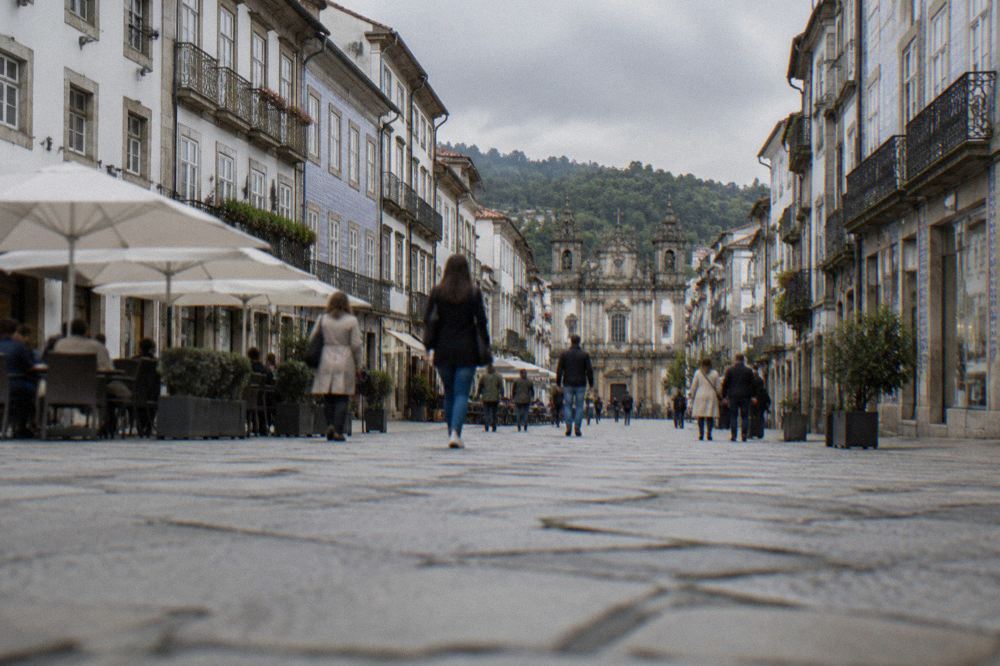 People walking along a wide pedestrian street with shop fronts and café terraces in Braga