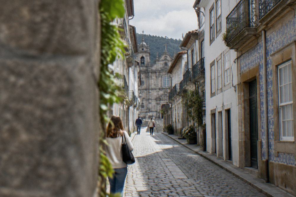 A narrow cobbled lane with old buildings leading uphill from a pedestrian street in Braga