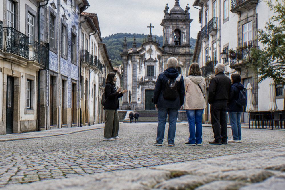 A guide speaking to a small group of visitors on a cobbled square in Braga