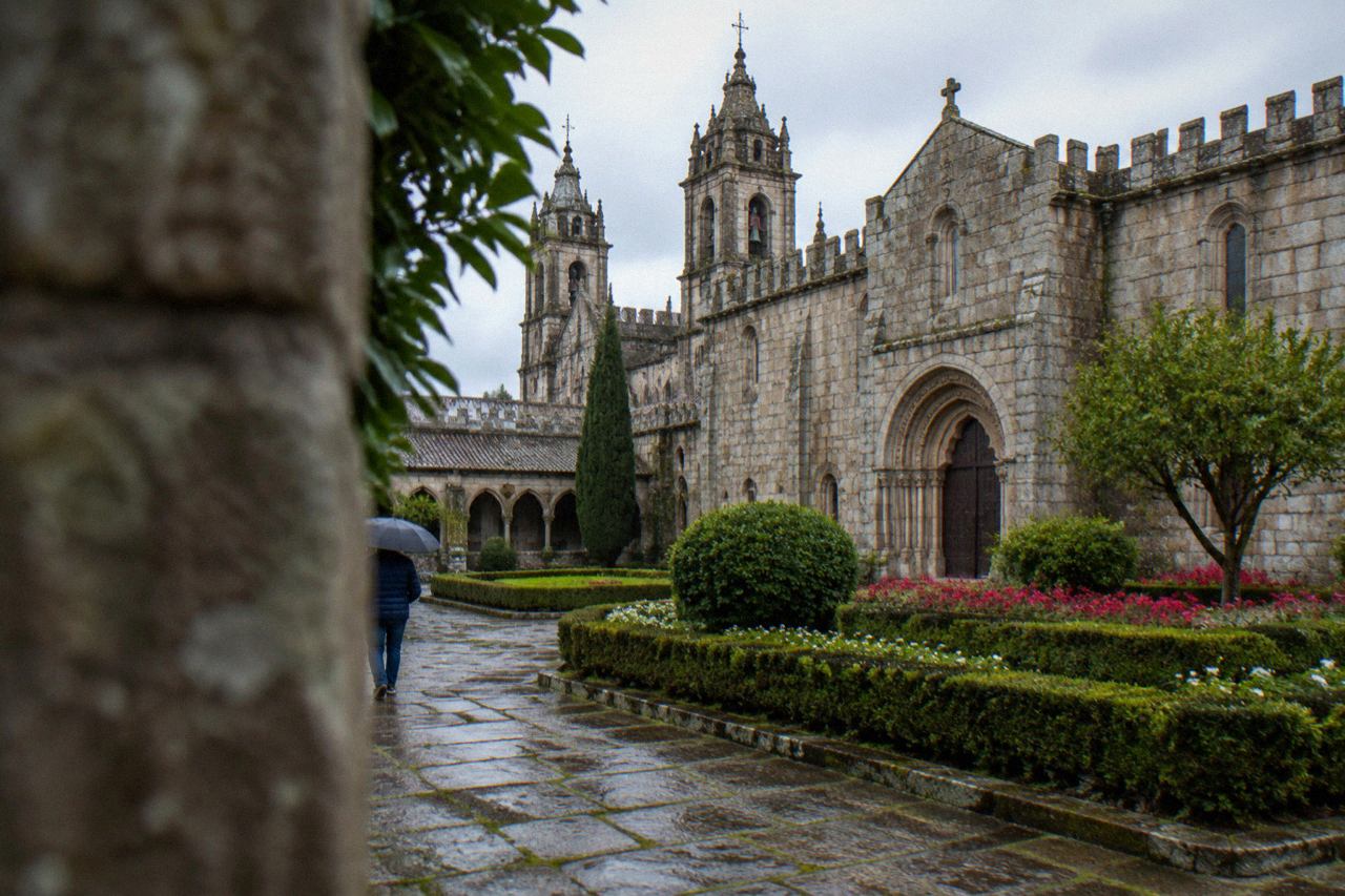 Formal flower beds and trimmed hedges in a city garden with the towers of Braga Cathedral rising behind