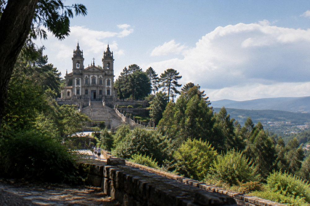 A hilltop church seen across green wooded countryside under a clear summer sky
