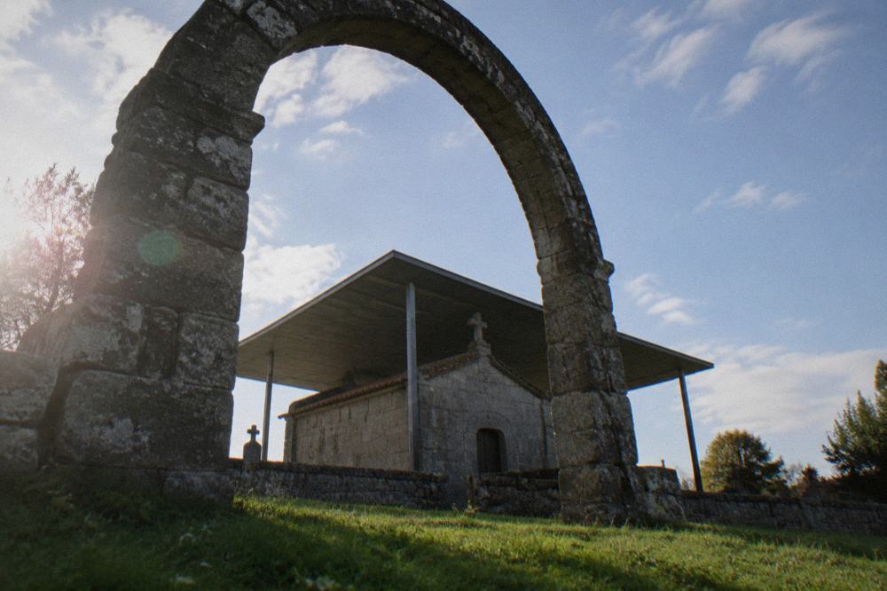 A stone archway of an early medieval chapel framed against a clear sky