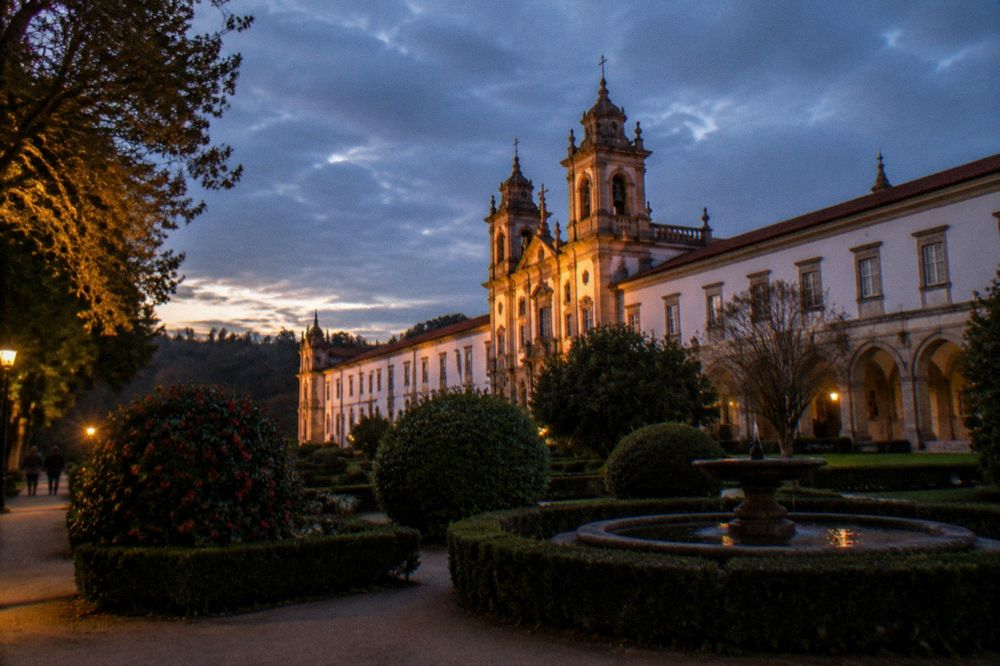 Evening sunlight falling across the monastery facade and trees at Tibães
