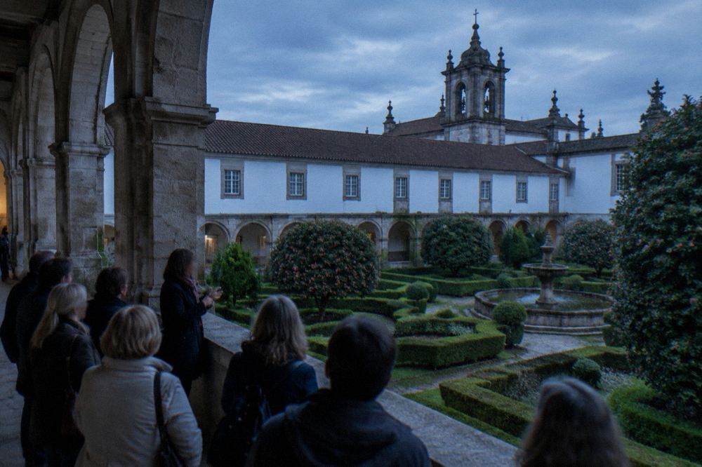 A guided group listening to a guide in a cloister at Tibães monastery