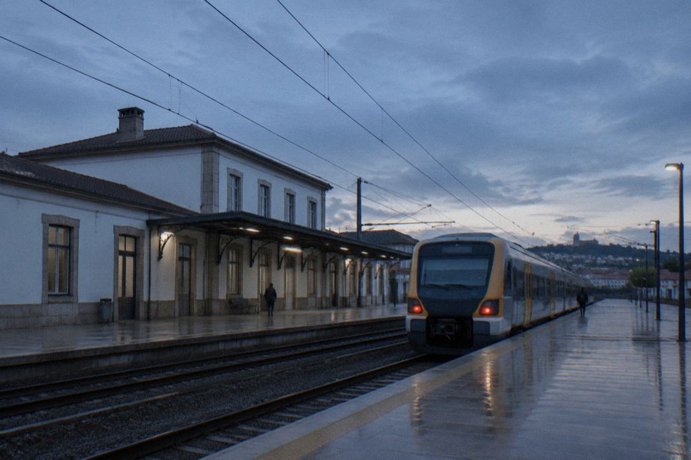 A regional train waiting at a Portuguese station platform in early morning light