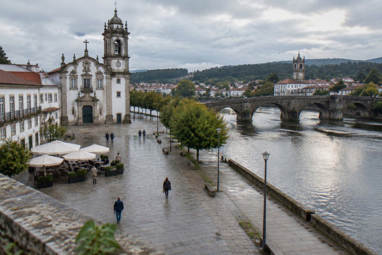 The medieval stone bridge and riverside of Barcelos with the town's church tower rising above the water