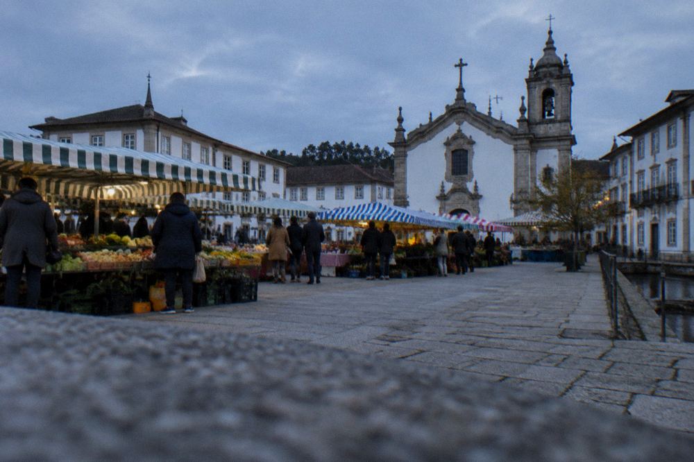 An open market square filled with striped vendor awnings and shoppers in a Portuguese town