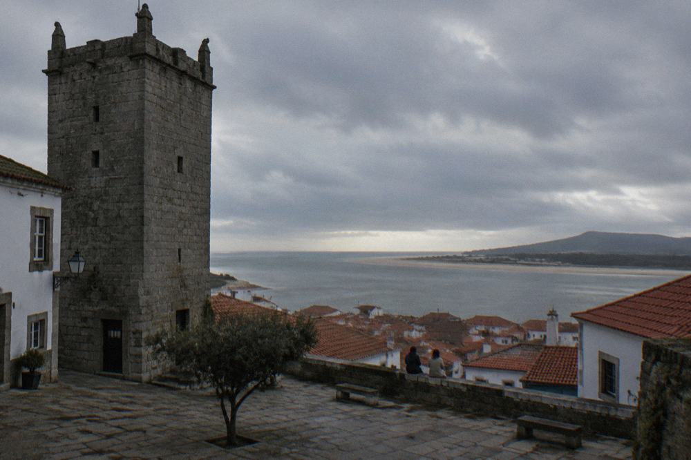 A view over red rooftops towards the wide estuary of the Minho River