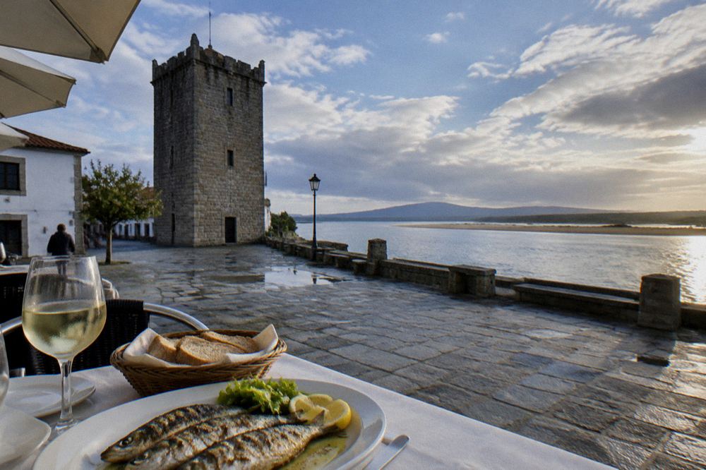 A table with grilled fish, white wine and bread at a small restaurant terrace