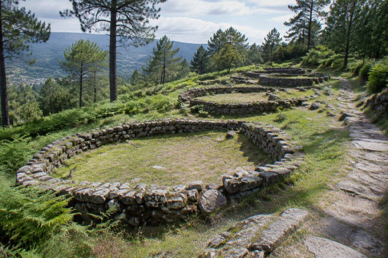 Stone footings of ancient round houses on a grassy hilltop at Citânia de Briteiros