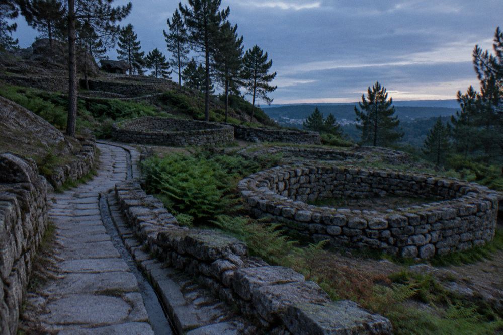 Paved ancient street with drainage channels running between stone house walls