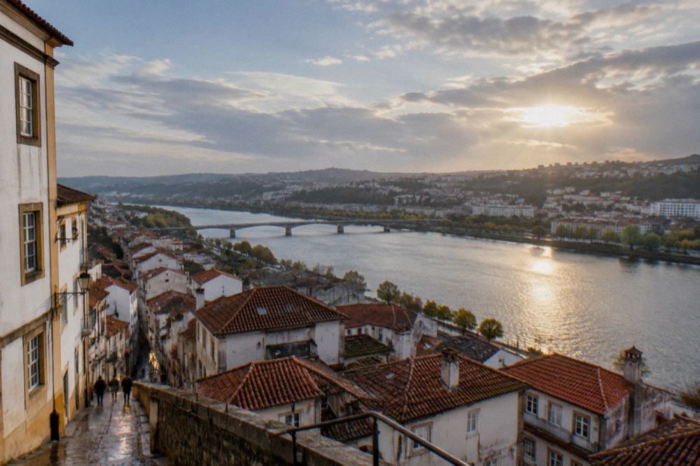 A view over Coimbra's red rooftops toward the Mondego river on a warm clear morning