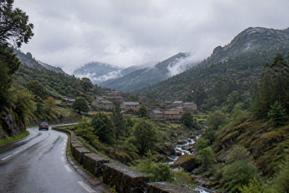 A mountain road winding through forest toward a village in the Gerês valley
