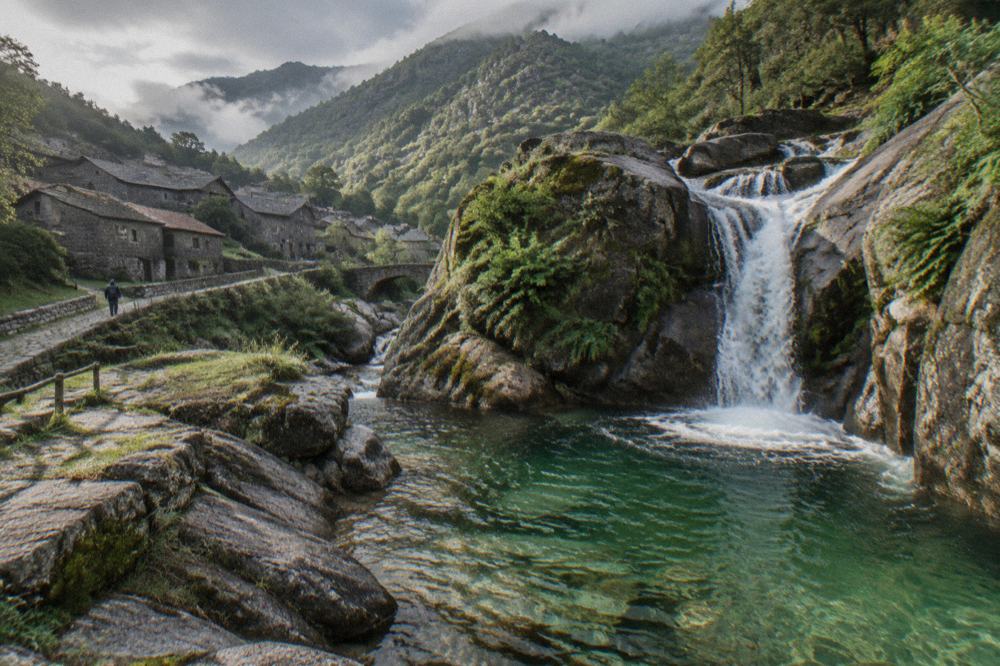 A waterfall dropping into a clear green pool between granite rocks
