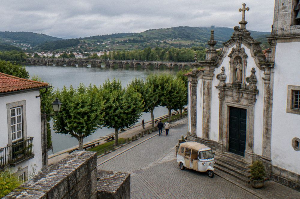 A three-wheeled tuk tuk vehicle parked on a cobbled street beside a baroque church facade