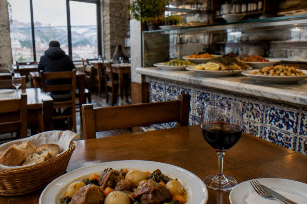 A traditional Porto restaurant interior with wooden tables and a counter of plated dishes
